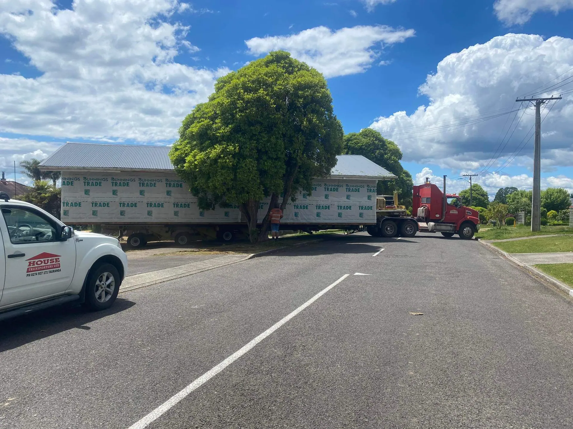 Squeezing large house around residential corner and trees with support pilot crew